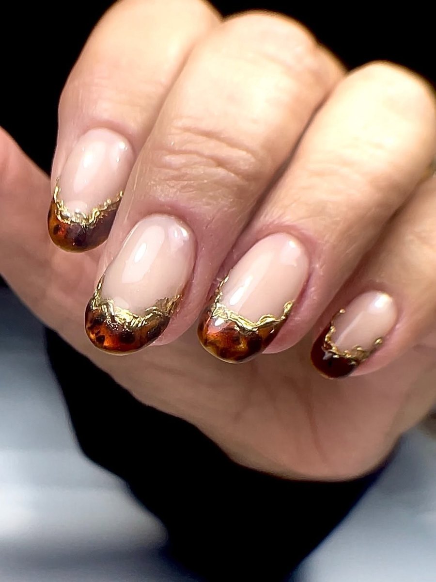 Short nude nails with amber tortoiseshell tips edged in gold foil